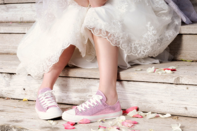 Wedding Dress and Pink Tennis Shoe Clad Body Sitting On Wooden Stairs . Elbows On Knees. Cute and Snappy.